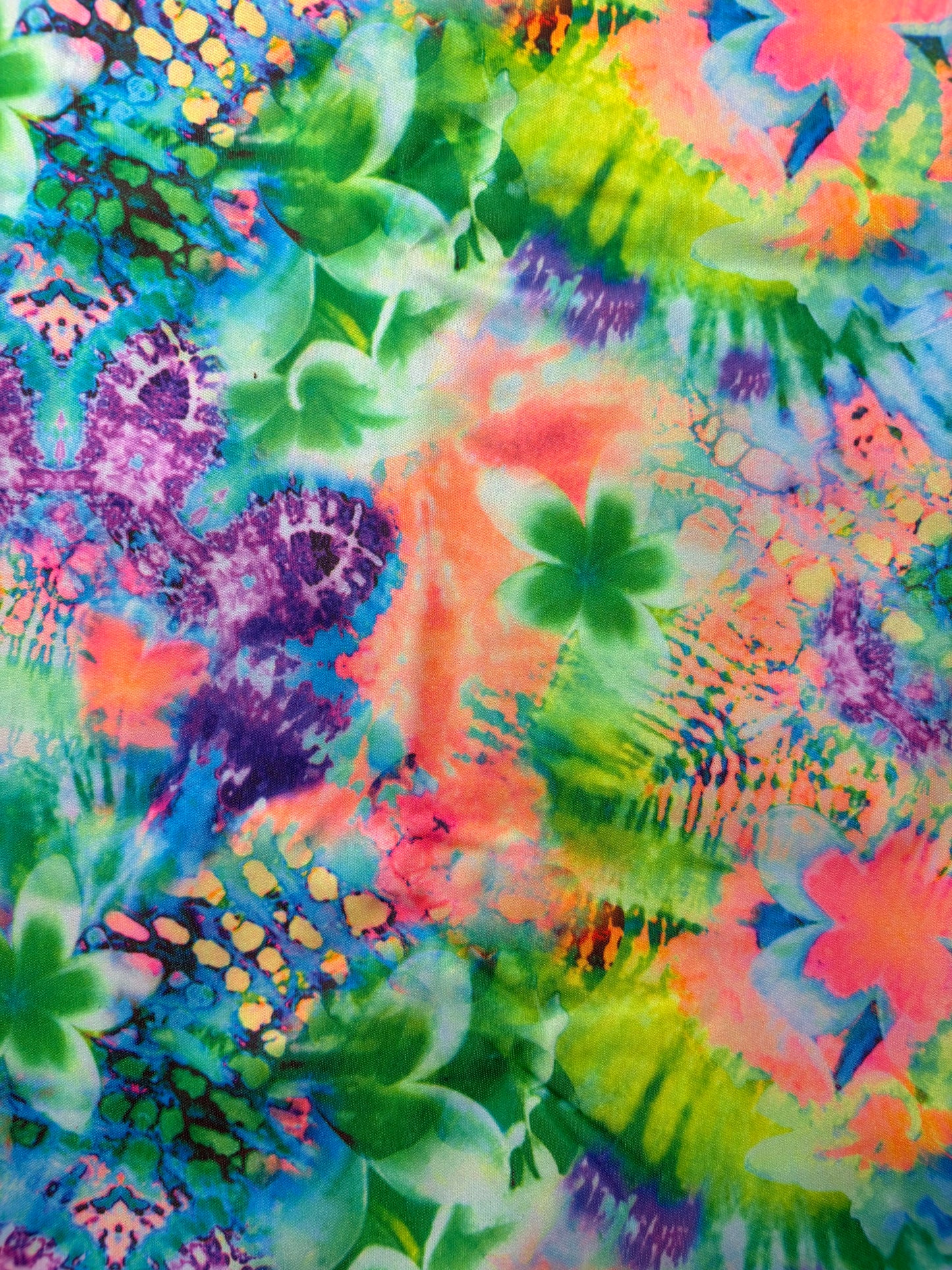 Colorful tie-dye pattern with green leaves on a multicolored background